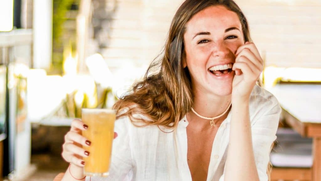 A woman laughing while holding a drink at a café.