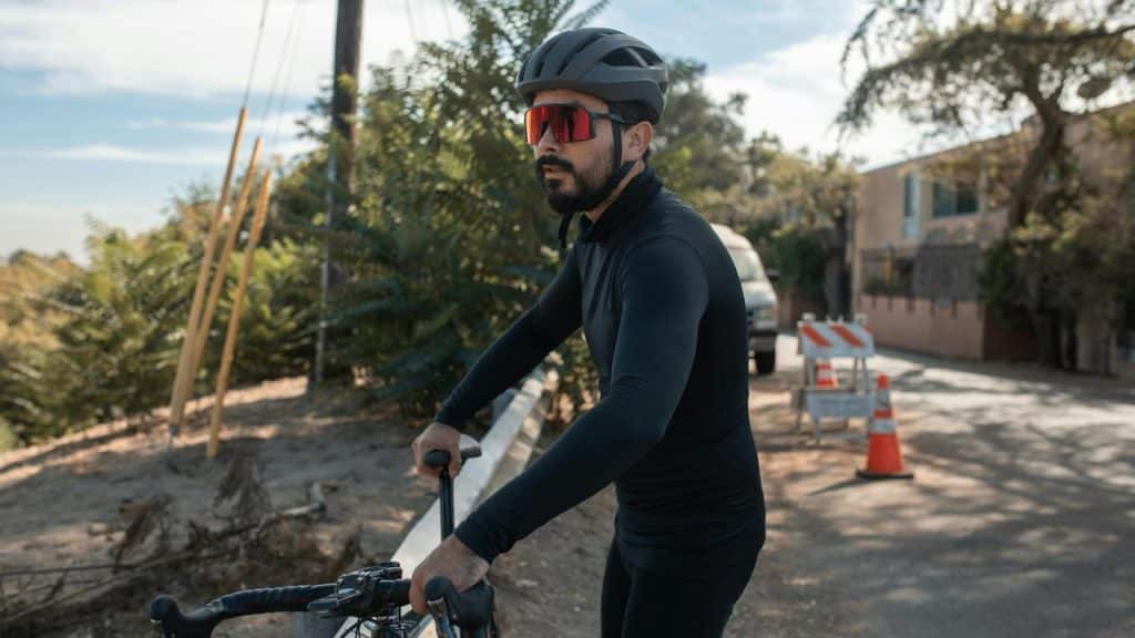 A cyclist wearing a helmet and sunglasses riding along a road.