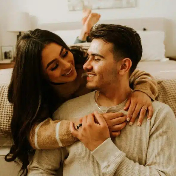 A man and a woman sitting on a bed with each other.