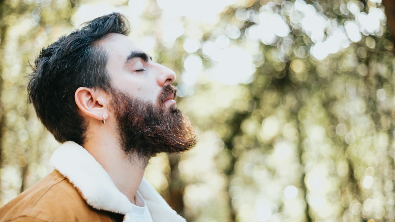 A bearded man looking upwards with his eyes closed and looking relaxed.