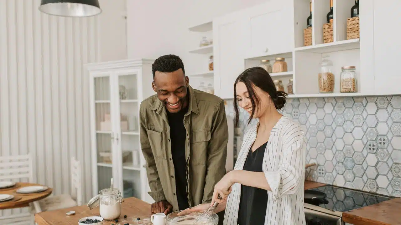 A couple smiling and cooking together
