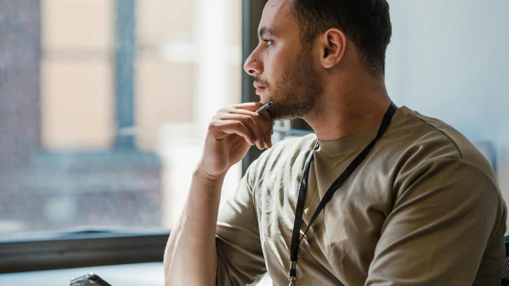 A man sitting by a window looking thoughtful.