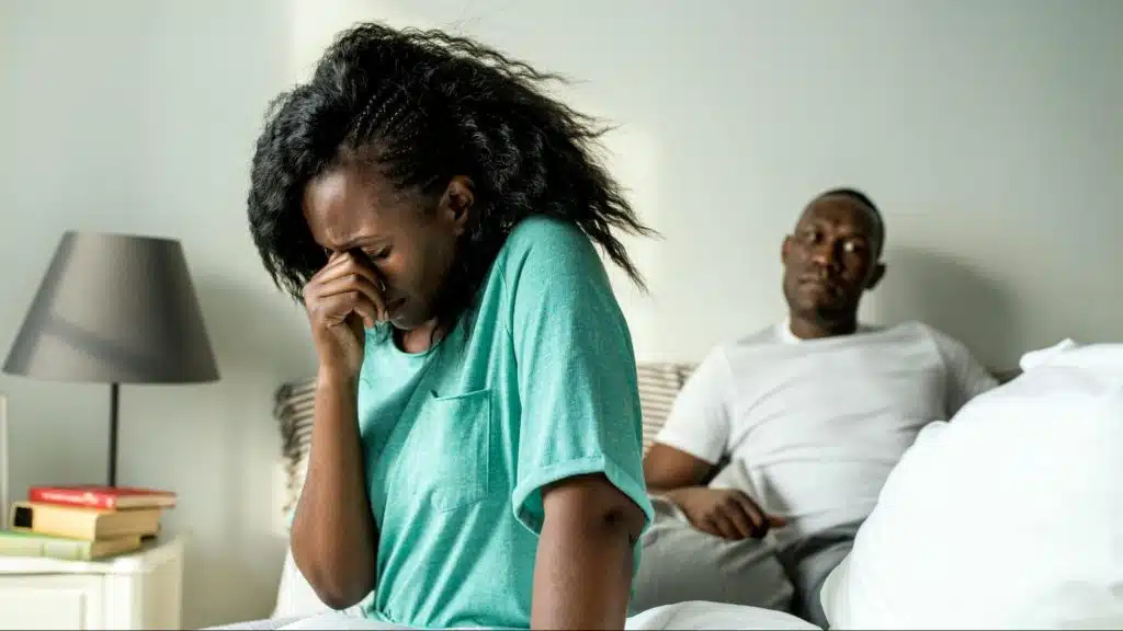 A woman crying and a man thinking behind her 