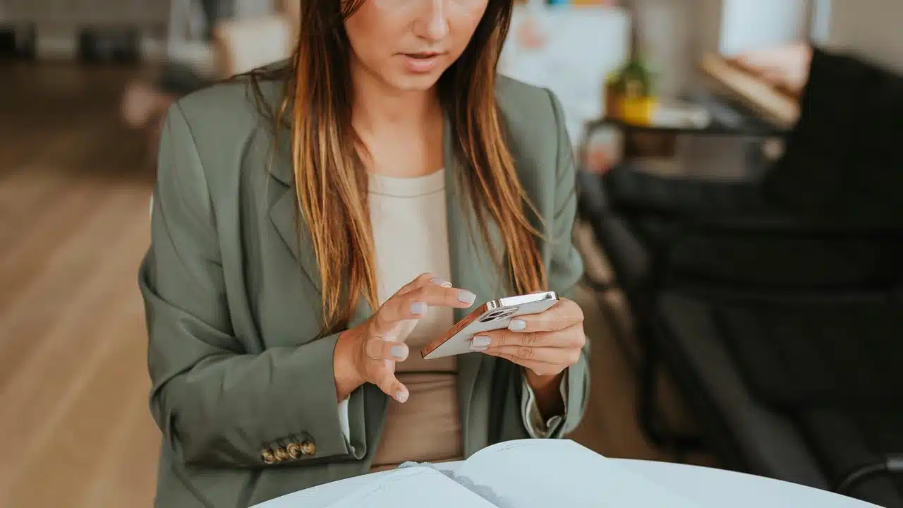A woman using her phone while reviewing documents