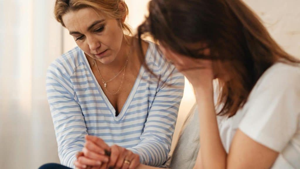 A woman comforting her upset friend while sitting together.