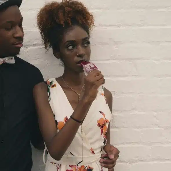 A man and a woman standing in front of a white-painted wall.