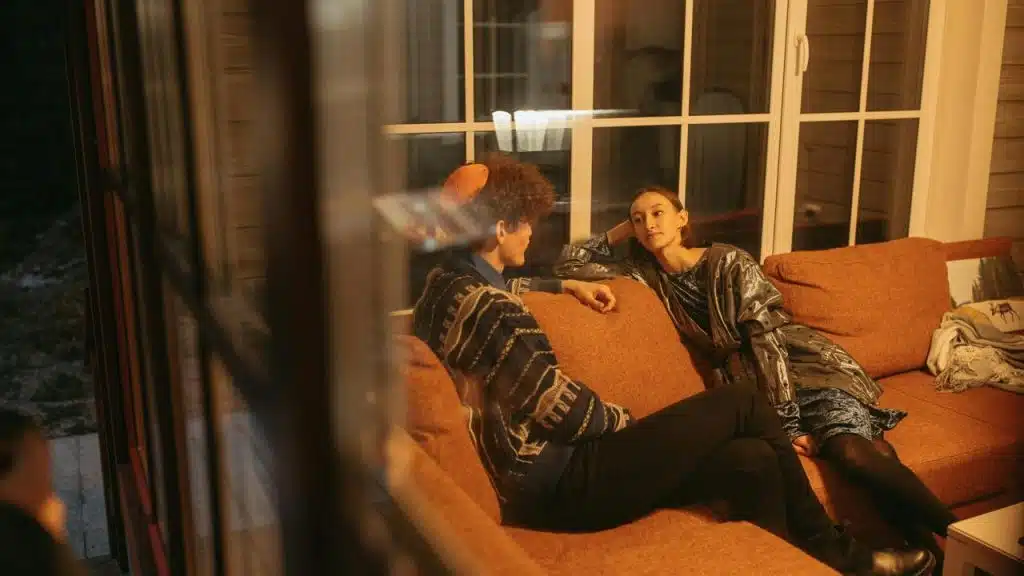 A couple sitting on an orange couch