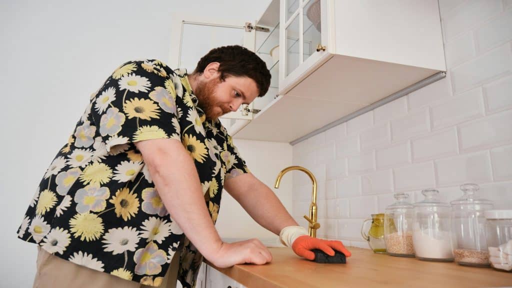 man cleaning kitchen thoughtfully
