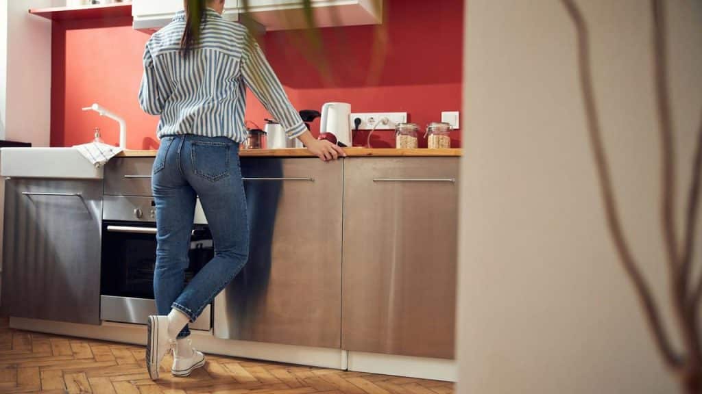 A woman standing in a kitchen leaning against the counter.