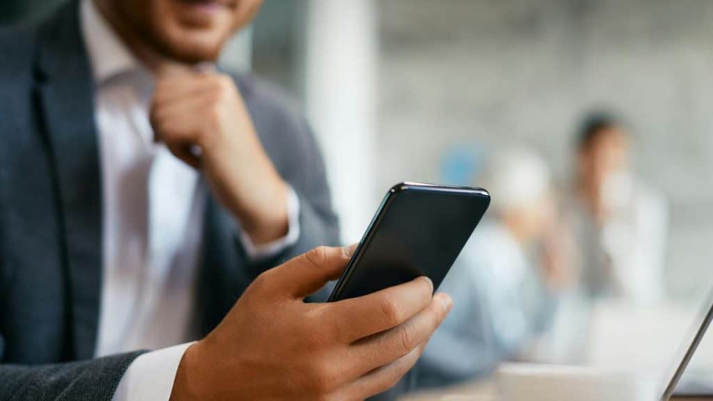 A businessman checking his smartphone while sitting in an office meeting.
