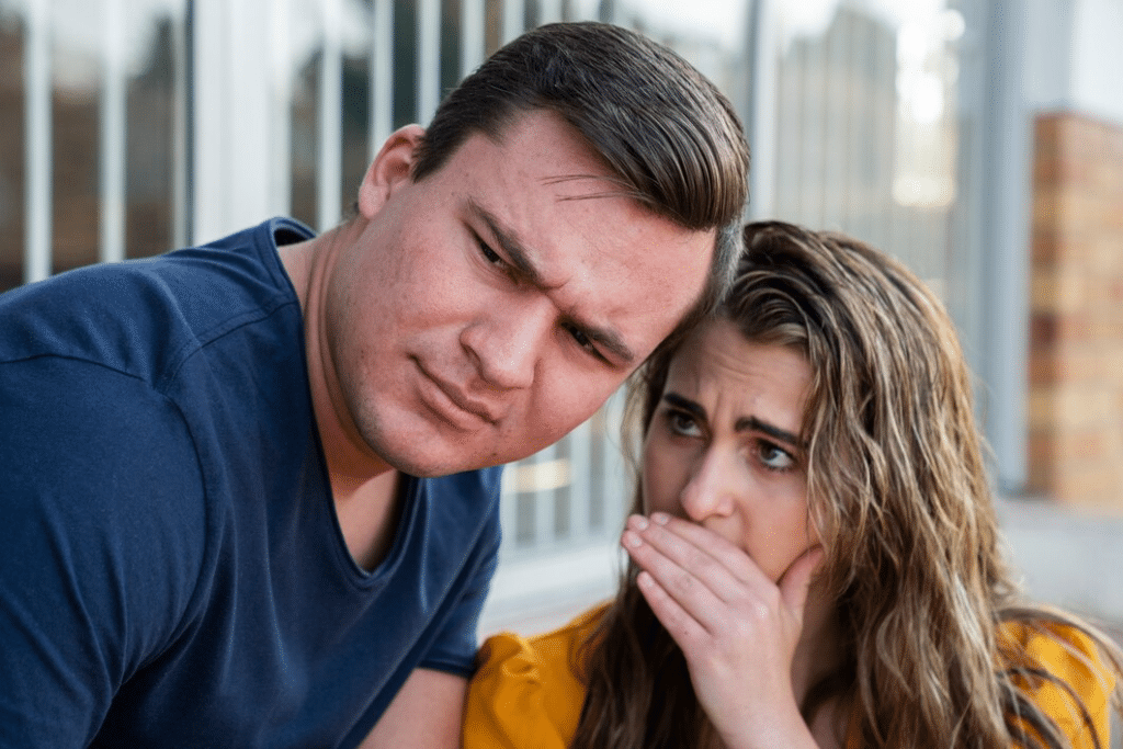 Woman whispering into man’s ear outdoors