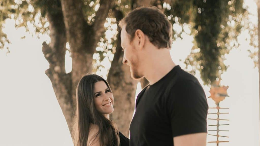 A man and a woman standing next to each other in front of a tree.