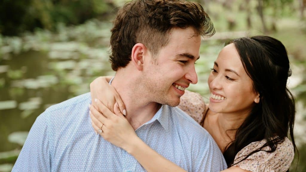 A woman smiling with her hand resting on a man's neck and shoulder.