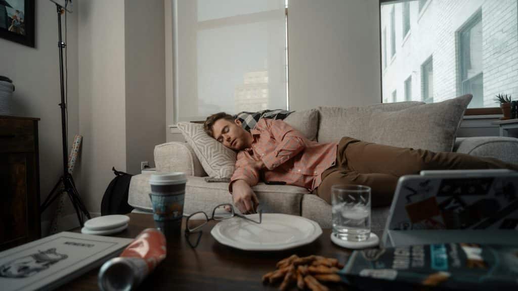 A woman lying on a couch with a plate of food.