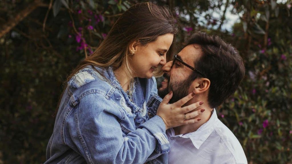A couple smiling with their foreheads touching in a garden.