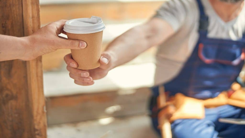 man handing coffee to partner