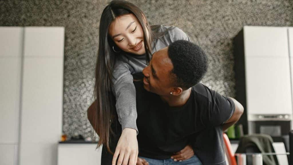 A couple playfully hugging in a kitchen.