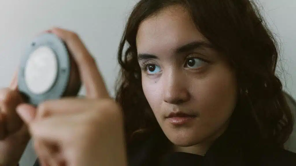 A woman looking at herself in a handheld mirror.
