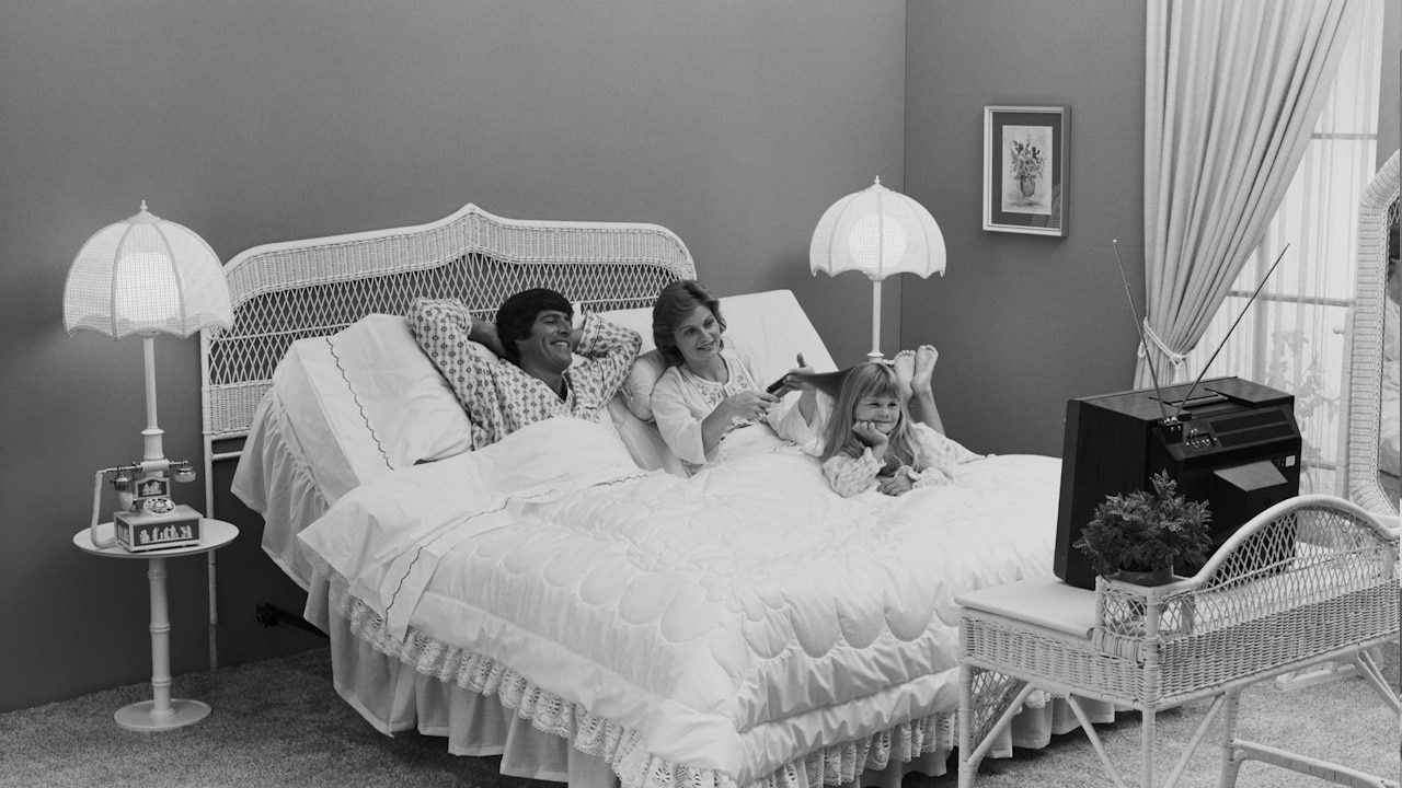 A black-and-white photo of two women and a child on a bed.