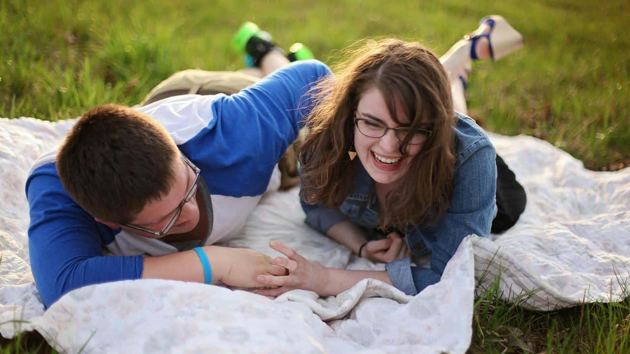 A couple lies on a blanket