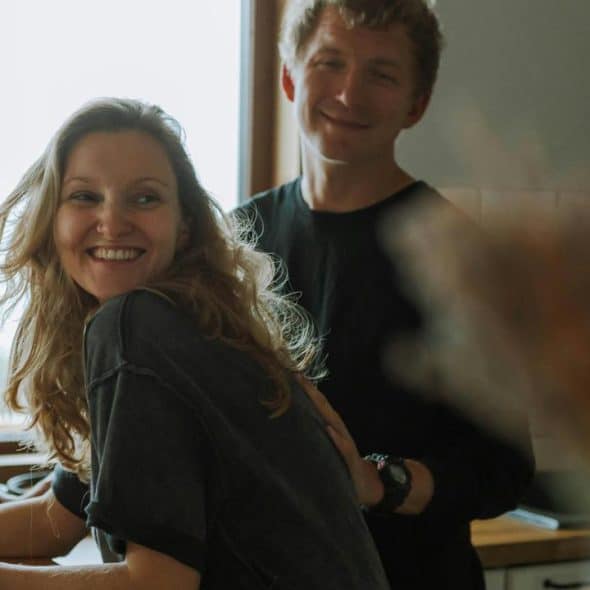 A smiling couple stands together in a cozy kitchen