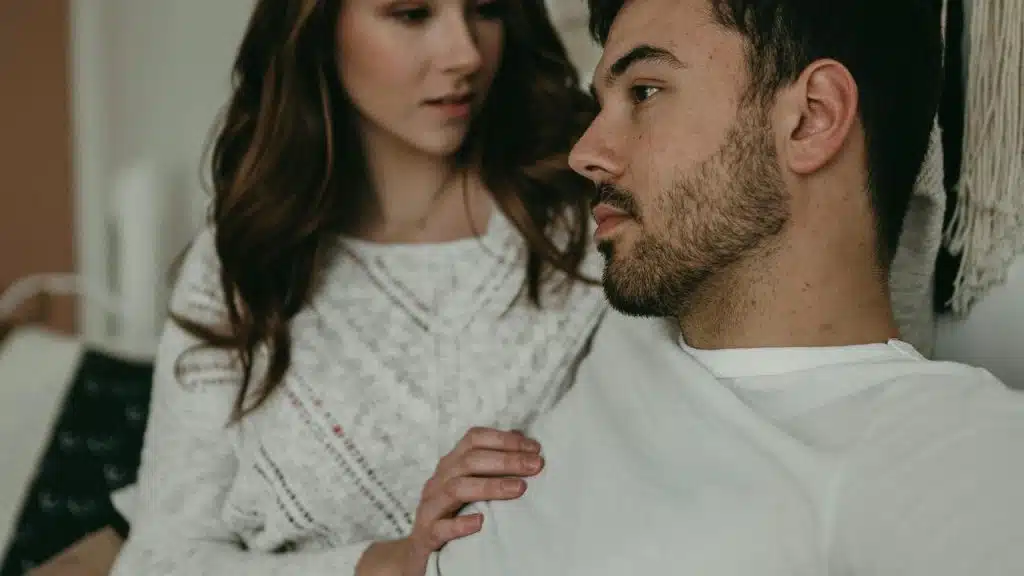 A woman gently touching a seated man’s shoulder