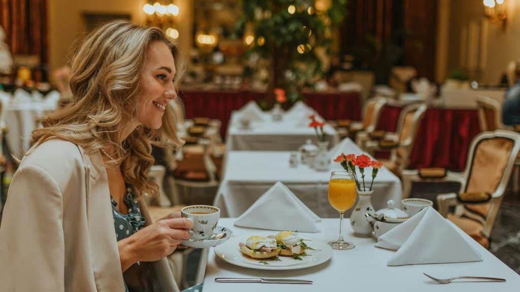 A smiling woman enjoying tea and a meal at an elegant restaurant table