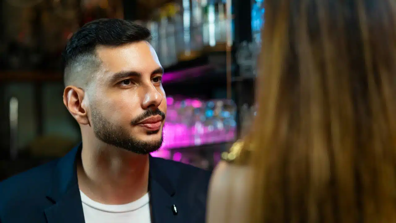 A man with a beard looks toward a woman who is seen from the back.