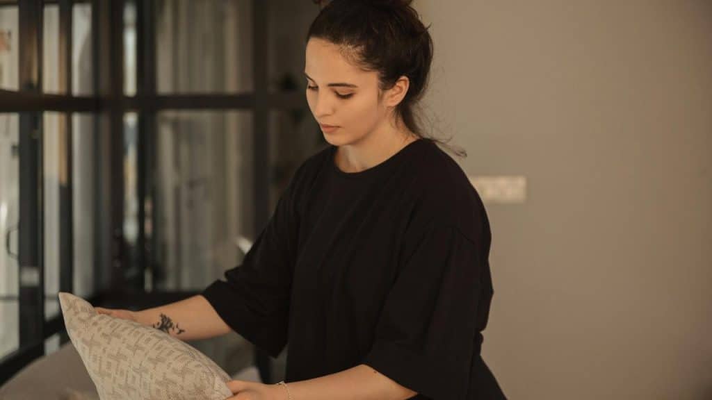 A woman arranging a cushion in a softly lit room.