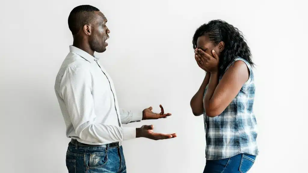 A couple having a fight. The woman is covering her face with her hands while crying.