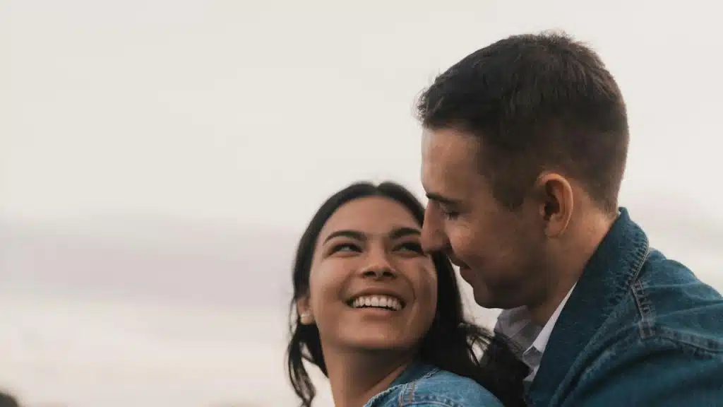 A smiling couple sharing a close, affectionate moment outdoors.