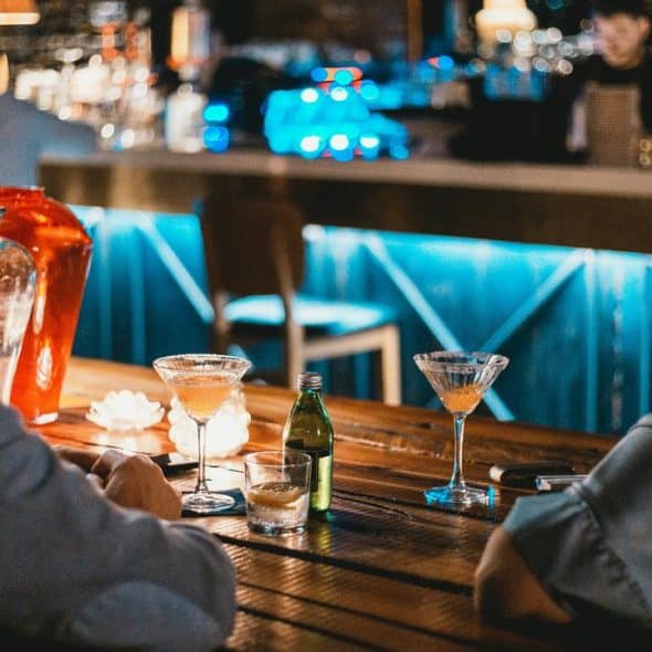 A couple sitting at a bar with cocktails