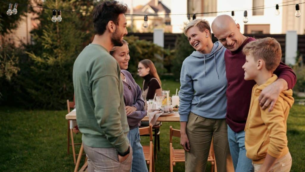 A family and friends chatting and smiling together at an outdoor gathering.
