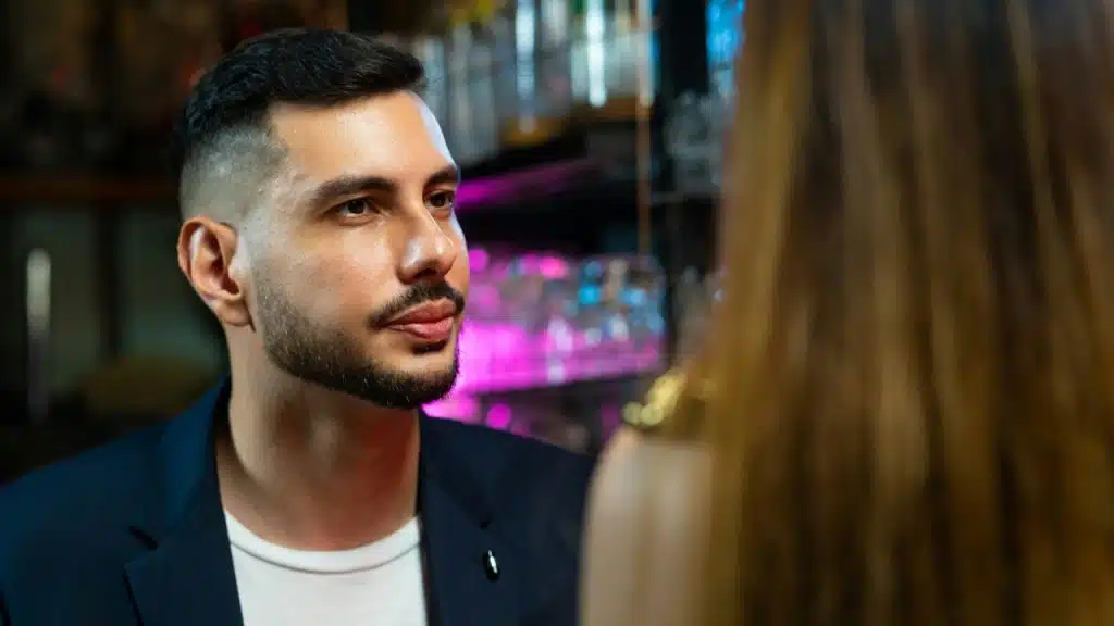 A man with a beard looking at a woman who is seen from the back.