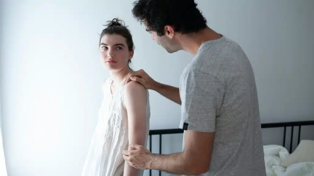 A man holding his wife’s arm in order to reconcile after a fight.