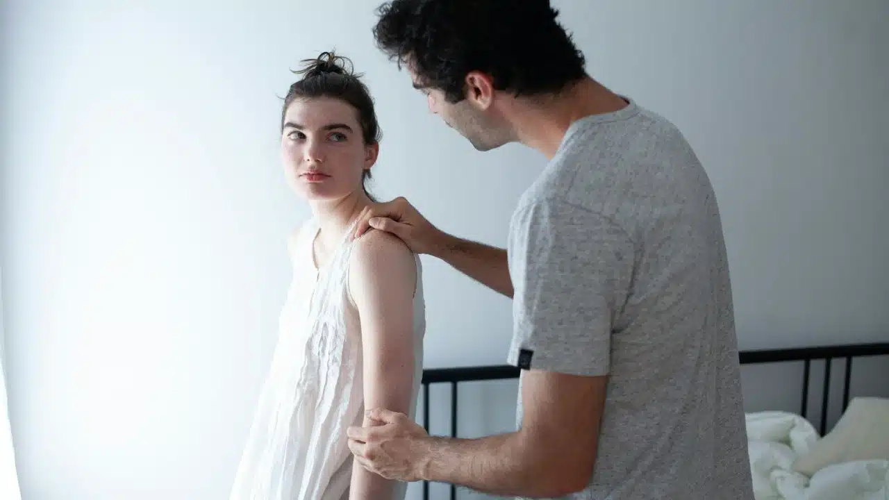 A man holding his wife’s arm in order to reconcile after a fight.