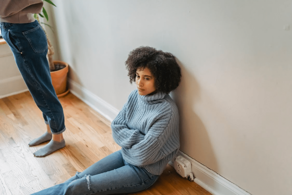 Upset black woman sitting on floor in room