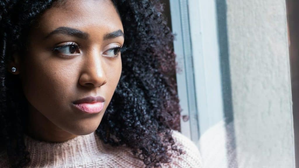 A woman gazing out a window with a thoughtful expression.