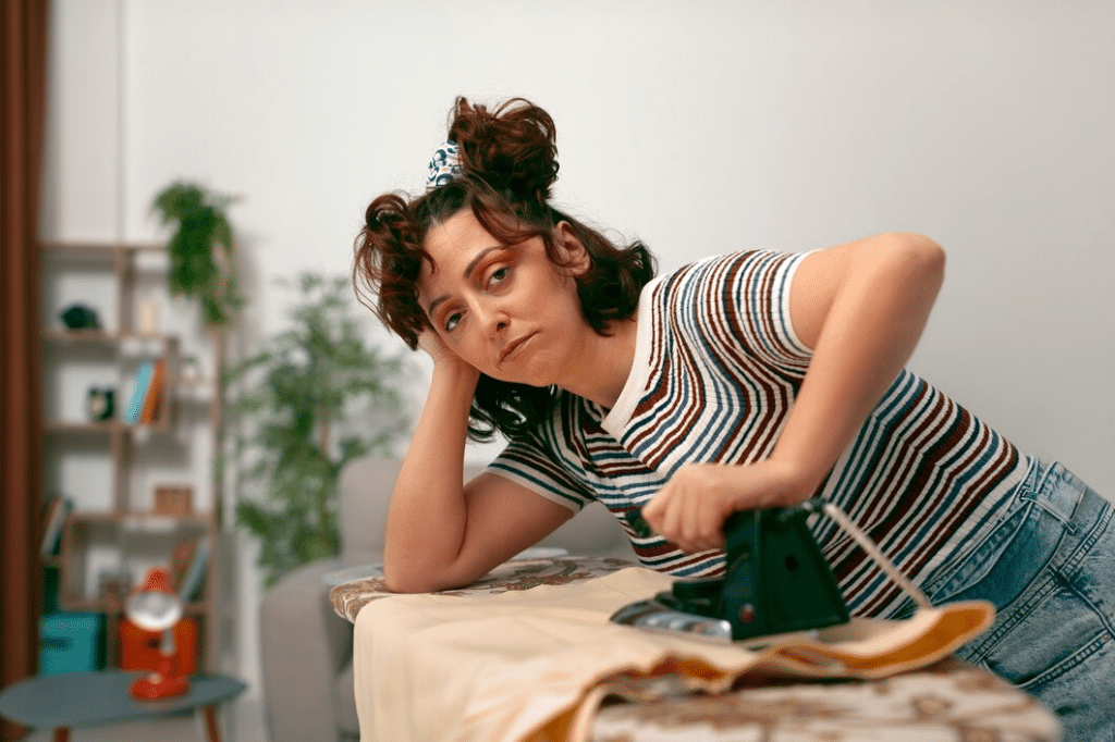 Tired Woman doing chores at home alone ironing clothes
