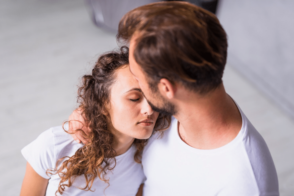 A man kissing woman’s forehead