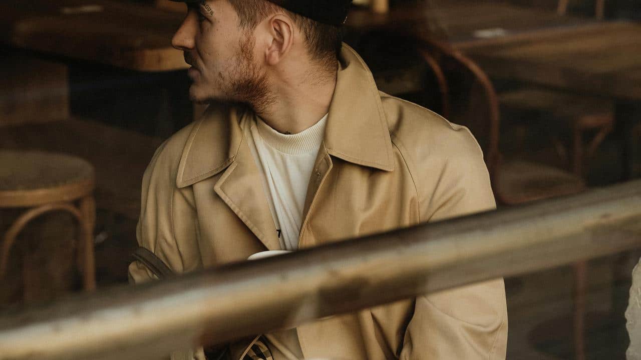 A man wearing a coat and cap sitting
