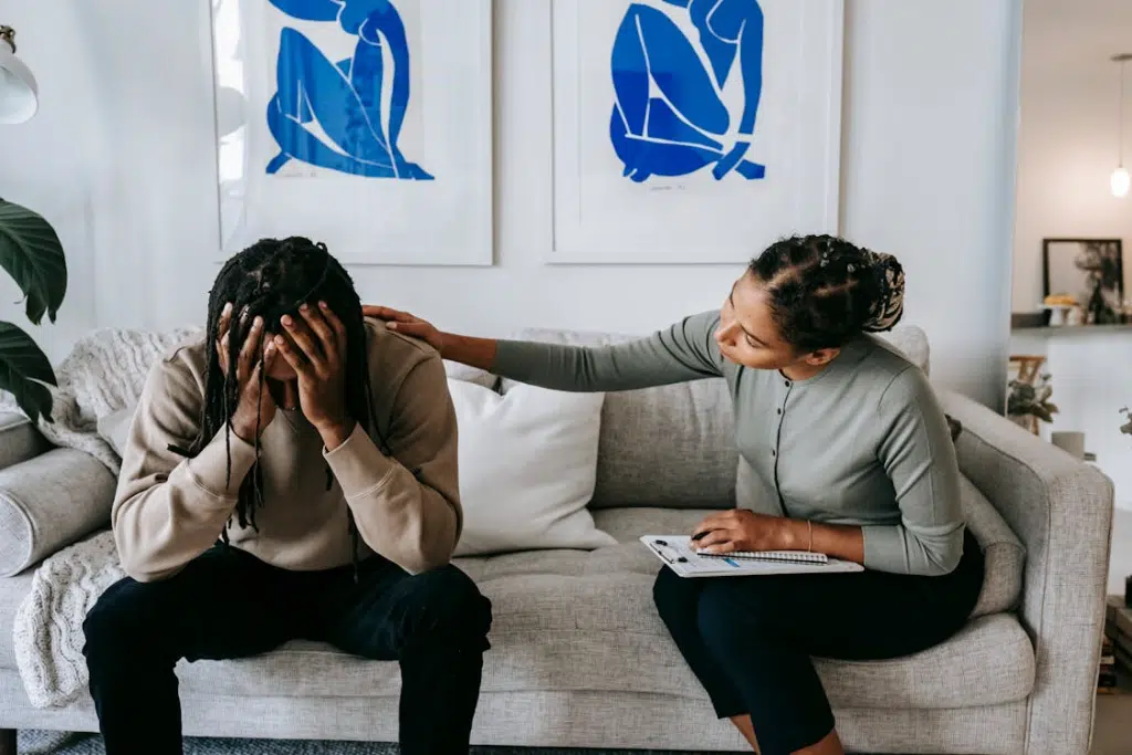 Woman consoling unhappy boyfriend on sofa at home