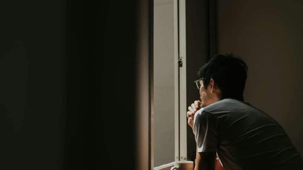 A man sitting by a window looking outside.