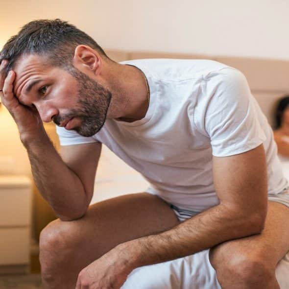 A man looking pensive as his wife looks at him