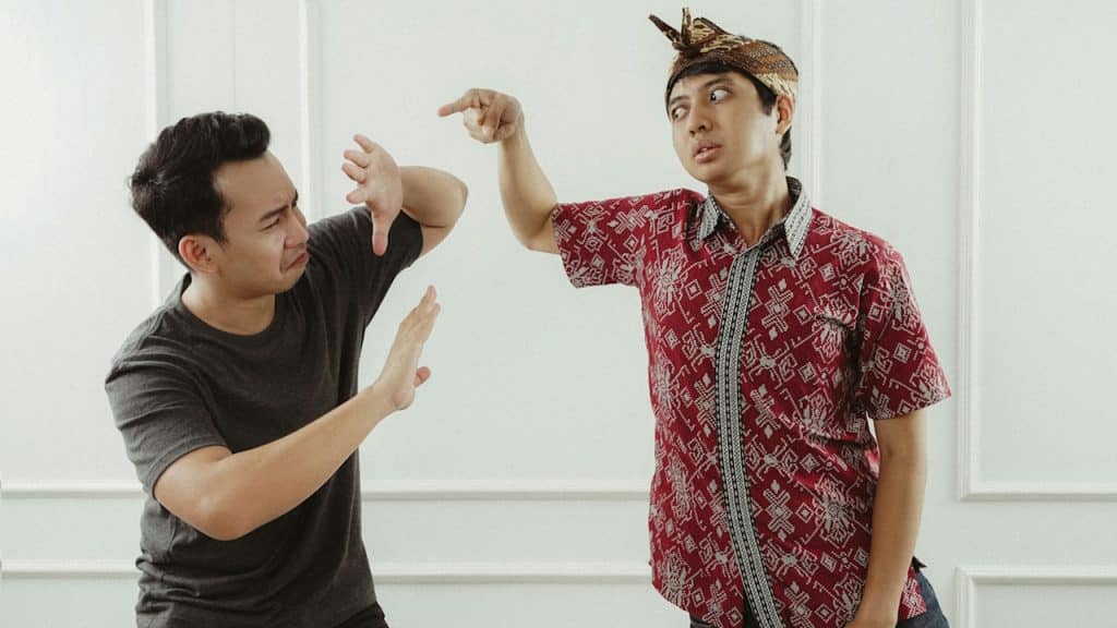 A man in a red-and-white button-up shirt is fighting with a man in a black T.shirt.