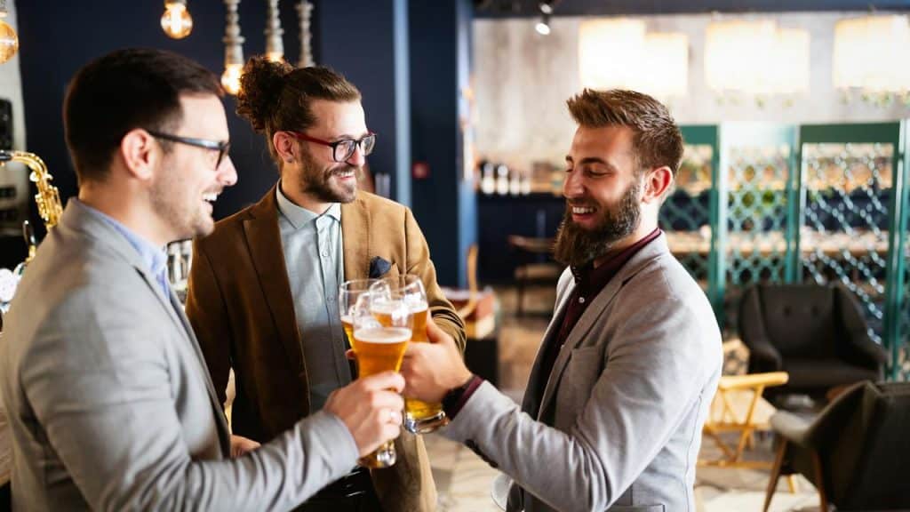 A group of men clinking glasses of beer while chatting in a bar.