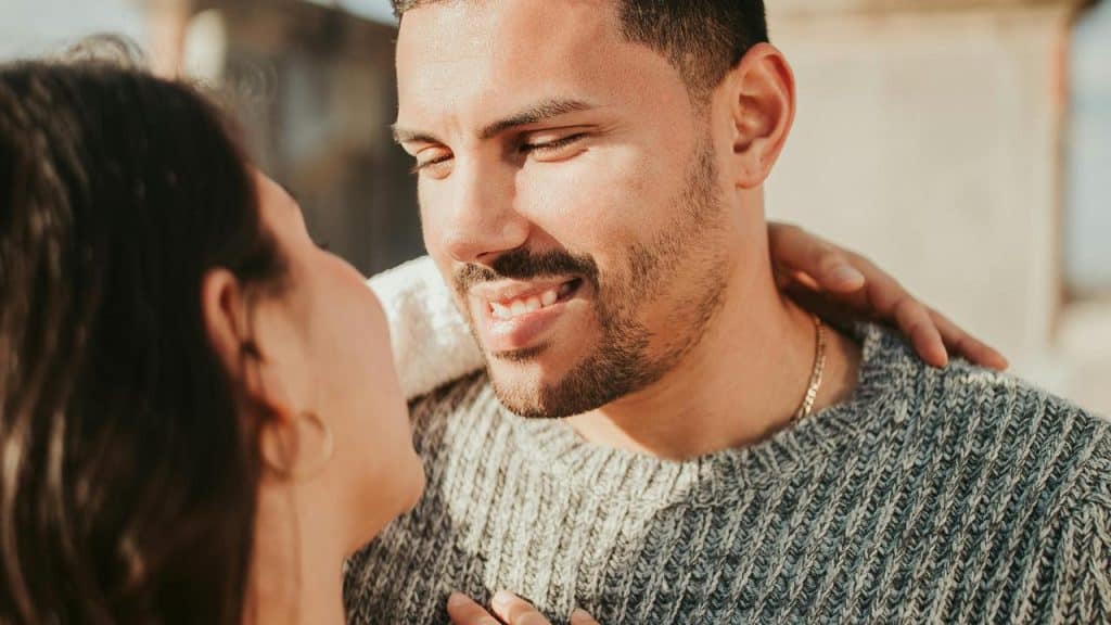 A smiling couple standing close together and looking at each other.