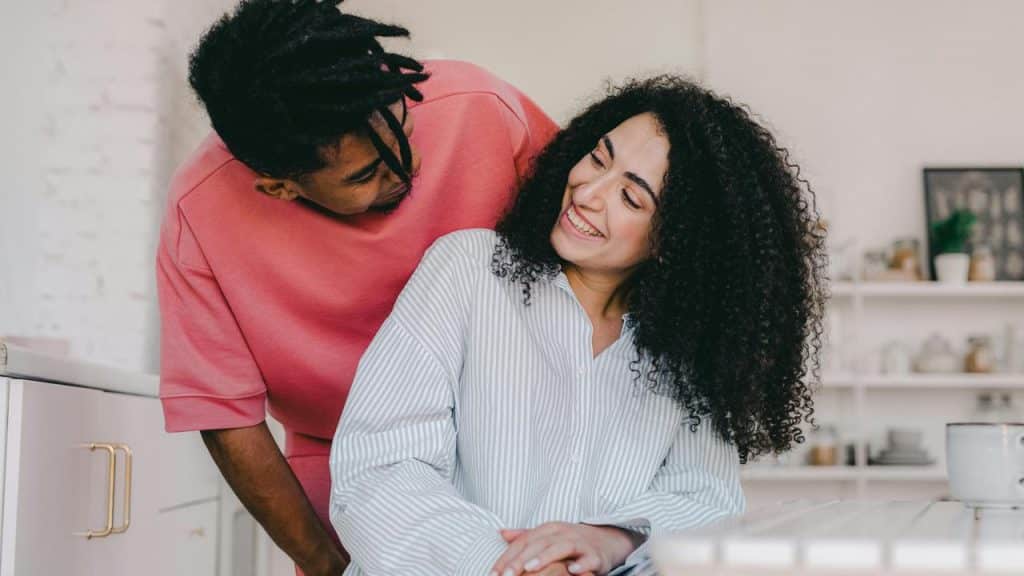 A smiling couple talking together in a bright kitchen.