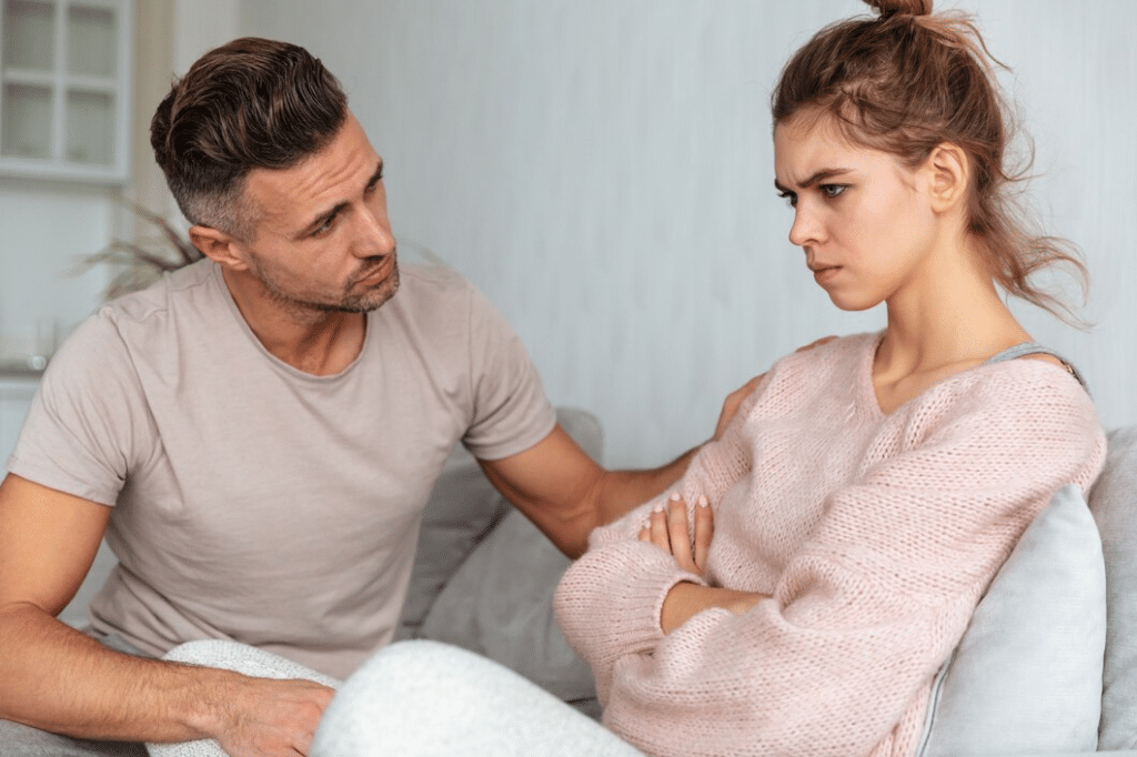 Man sitting on couch and calm down his offended girlfriend at home