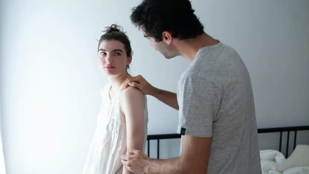 A man holding his wife’s arm in order to reconcile after a fight.